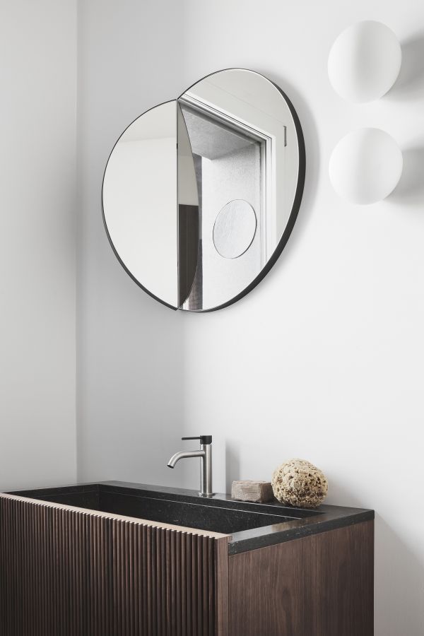 La salle de bain est tout aussi simple et élégante, avec un miroir mural chic et une vanité en bois