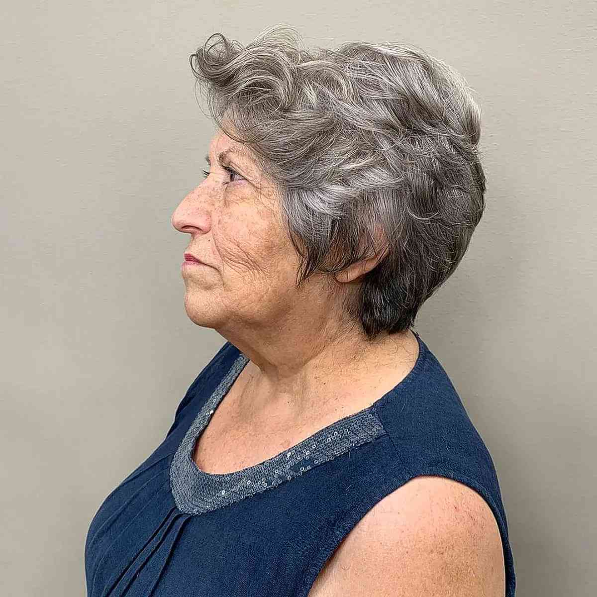 Lutin gradué ondulé sur cheveux gris pour une femme dans la soixantaine